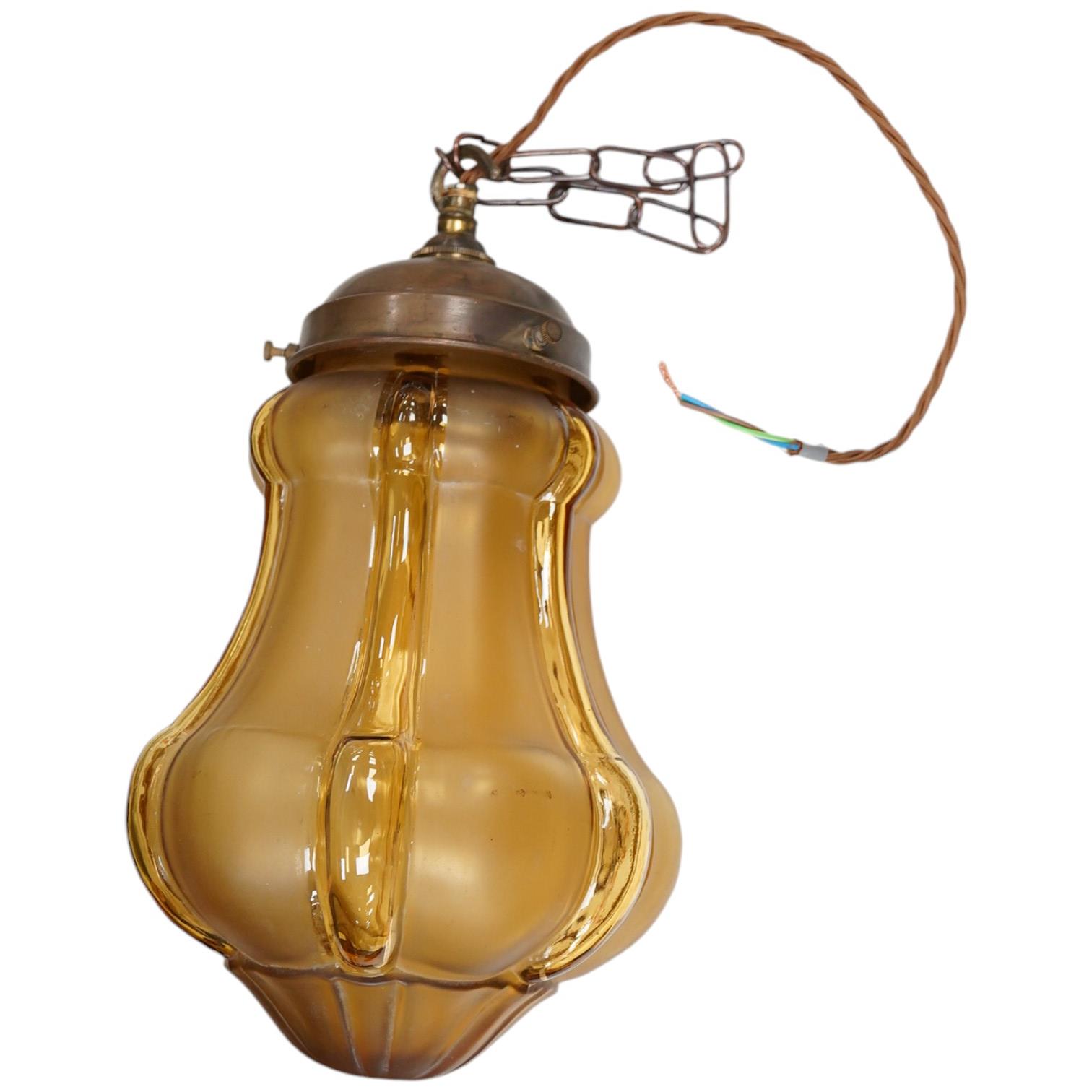 A large English amber colour glass pendant with original antique brass fitting, chain and ceiling rose, circa 1930, wired, 33cm high to top of gallery, 18cm wide. Condition - good